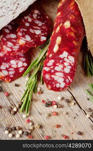 Dry sausage with sliced pieces on wooden table