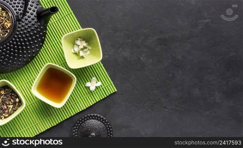 dry tea herb herbal tea with white jasmine flower green placemat black backdrop