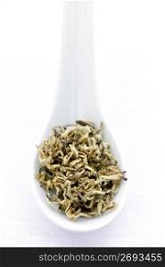 Dry white tea leaves in a spoon