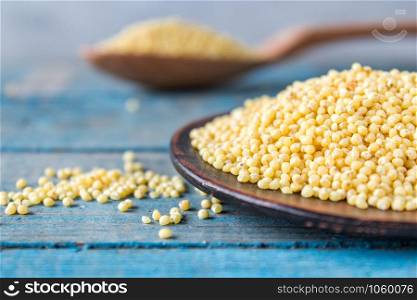 Dry yellow millet in a bowl on a background of old blue boards. Close-up.. Dry yellow millet in a bowl on a background of old blue boards.