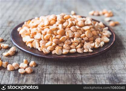 Dry yellow peas in a bowl on old boards. Chipped yellow peas are used for cooking. Close-up.. Dry yellow peas in a bowl on old boards. Chipped yellow peas are used for cooking.