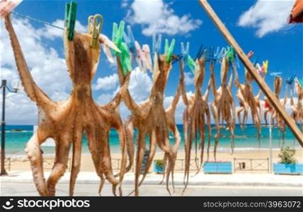 Drying octopus on the clothesline with clothespins on a beach background. Crete, Greece.