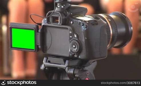 DSLR camera in recording mode with green screen