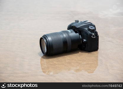 DSLR camera with telephoto lens on a beach it wet from water sea wave when travel and test using in the extreme environment demo waterproof by photographer. DSLR camera on beach wet from water sea wave