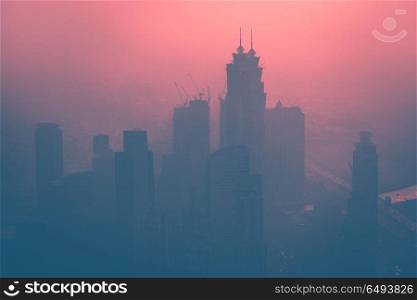 Dubai at dusk, cityscape with high-rise towers in the fog over beautiful pink sunset background. Dubai at dusk