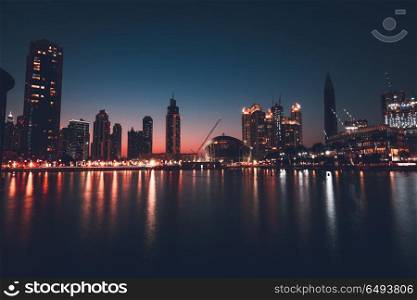 Dubai downtown at night, beautiful glowing lights from the towers reflected in the water, amazing nighttime cityscape. Dubai downtown at night