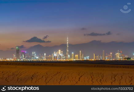 Dubai Downtown skyline with desert sand, United Arab Emirates or UAE. Financial district and business area in smart urban city. Skyscraper and high-rise buildings at sunset.