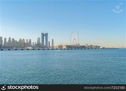 Dubai Downtown skyline with waves on sea beach, United Arab Emirates or UAE. Financial district in travel vacation concept. Urban city. Skyscrapers buildings with sunset sky.