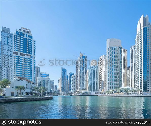 Dubai Marina and lake or river, Downtown skyline, United Arab Emirates or UAE. Financial district and business area in smart urban city. Skyscraper and high-rise buildings with blue sky. Architecture.