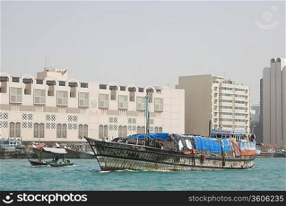 Dubai, UAE, A dhow, an old wooden sailing vessel, filled with cargo leaves the dock in Deira.