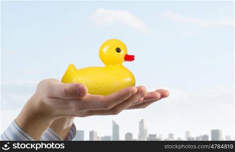 Duck in hand. Hand holding yellow toy rubber or plastic duck
