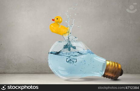 Duck toy. Glass light bulb and yellow rubber toy inside on blue background