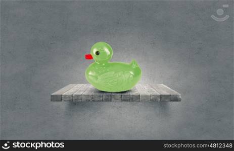 Duck toy. Green rubber duck toy on wooden board