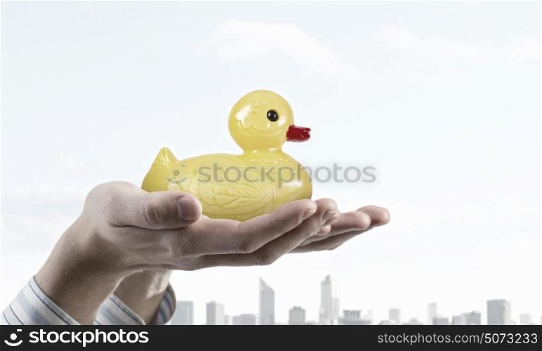 Duck toy in hands. Hand holding yellow toy rubber or plastic duck