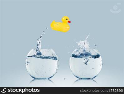 Duck toy. Yellow rubber duck toy jumping from one aquarium to another