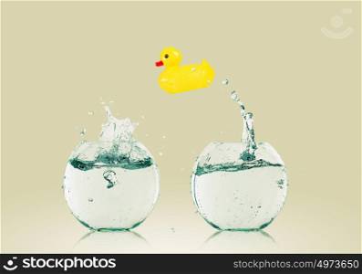 Duck toy. Yellow rubber duck toy jumping from one aquarium to another