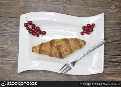 Dukan Diet. Fresh delicious croissant at Dukan Diet on a porcelain plate with a spoon on a wooden background.. Dukan Diet. Fresh delicious croissant at Dukan Diet on a porcelain plate with a spoon on a wooden background
