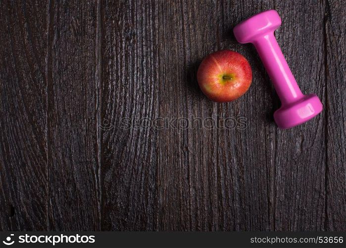 Dumbbell and apple on dark wooden background. Fitness wear and equipment. Sport fashion, Sport accessories, Sport equipment. for healthy concept