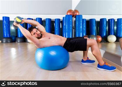 Dumbbell bench press on fit ball man workout at fitness gym