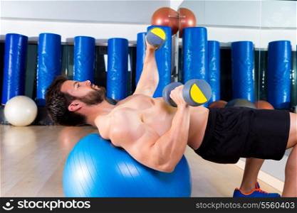 Dumbbell chest press on fit ball man workout at fitness gym