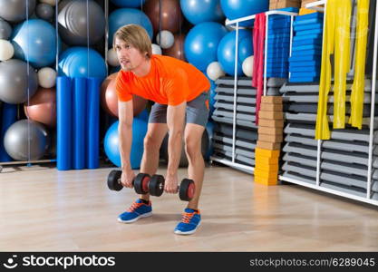 dumbbell deadlift blond man at gym weightlifting with swiss ball background