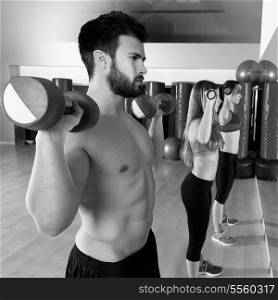 Dumbbell weightlifting man and women workout group at gym looking at mirror