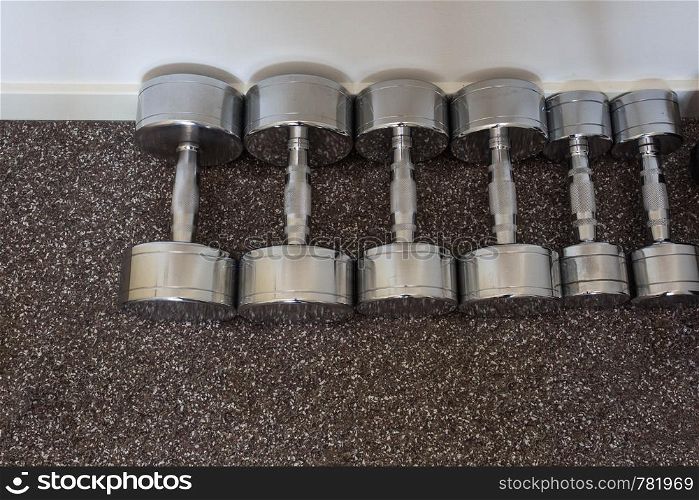 Dumbells on the floor in fitness room, close-up. Dumbells on the floor in fitness room,