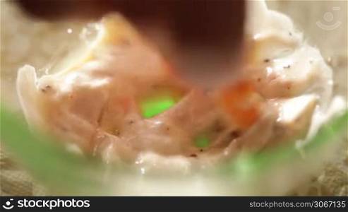 Dunking a shrimp in a white sauce.