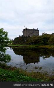 Dunvegan Castle reflected in Dunvegan Loch in Scotland.