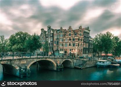 Dusk city view of Amsterdam canal, bridge and typical houses, boats and bicycles, Holland, Netherlands... Toning in cool tones