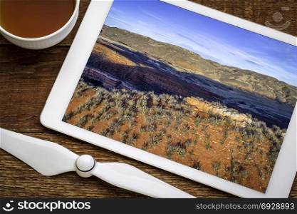 dusk over foothills of Rocky Mountains in northern Colorado with red sandstone and canyons, reviewing aerial image on a digital tablet