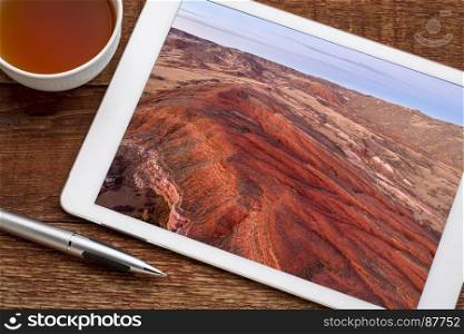 dusk over foothills of Rocky Mountains in northern Colorado with red sandstone and canyons, reviewing aerial image on a digital tablet