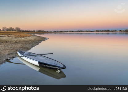 dusk over lake in Colorado with a stand up paddleboard on a beach