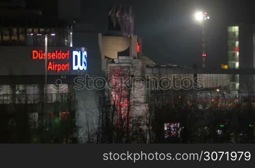 Dusseldorf Airport Building at night. City view with illuminated sign, trees and lantern light