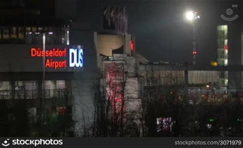 Dusseldorf Airport Building at night. City view with illuminated sign, trees and lantern light