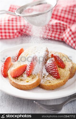 dusting powder sugar over french toast with strawberry