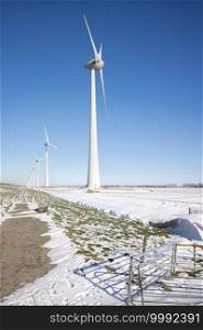 Dutch agricultural landscape wind turbines and fields covered with snow in winter time. Dutch agricultural landscape with windturbines and fields covered with snow