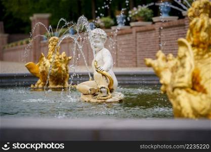 Dutch baroque garden of The Loo Palace , a former royal palace and now a national museum located in the outskirts of Apeldoorn in the Netherlands. APELDOORN - SEPTEMBER 2021  Baroque Fountain with golden details in the garden of the Royal Loo Palace September 23, 2021 in Apeldoorn, the Netherlands