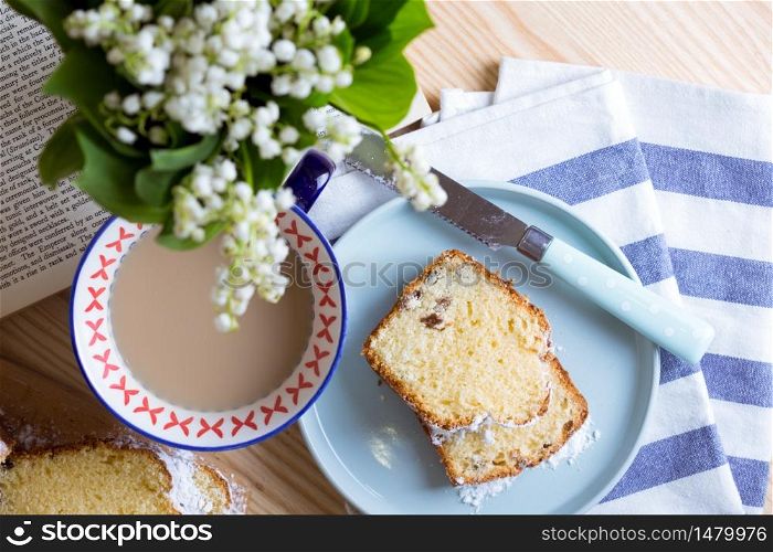 dutch cake and cup of tea and a bouquet of lilies of the valley on the table