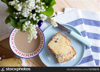 dutch cake and cup of tea and a bouquet of lilies of the valley on the table