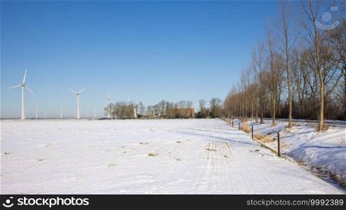 Dutch farmland covered by white snow with farmhouse and wind turbines. Dutch farmland covered by snow with farmhouse and wind turbines