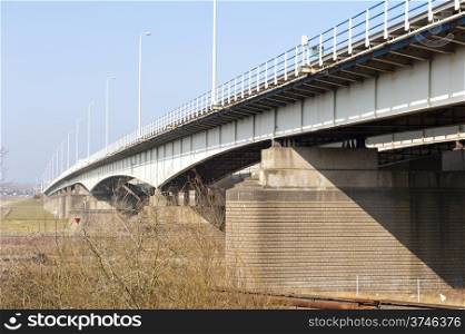 Dutch highway bridge with brick pillars crossing the river Rhinel at the city of Arnhem, the Netherlands.