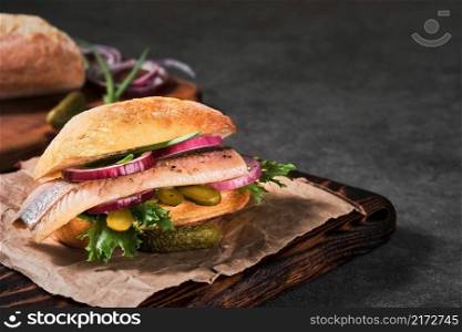 Dutch sandwich with herring and pickles pickled cucumber and red onion on the gray table. Close up, selective focus and copy space