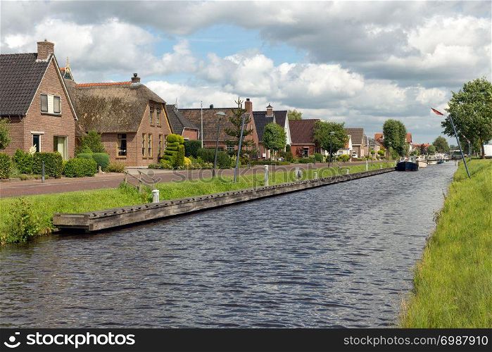 Dutch village Appelscha in Friesland with houses along a canal and a beautiful cloudy sky. Dutch village Appelscha in Friesland with houses along a canal