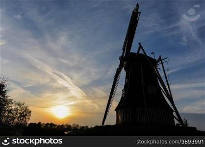 Dutch windmill at sunset with blue sky and golden sun