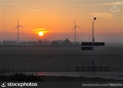 Dutch windmills at winter sunrise at a road intersection