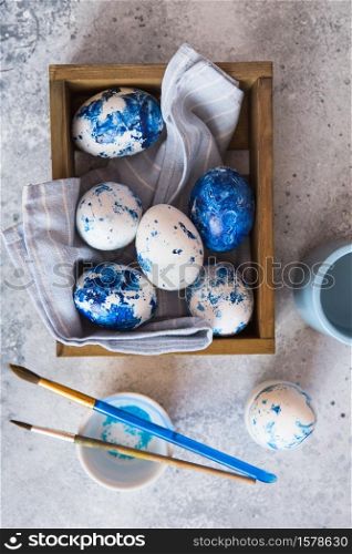 Dyed Easter eggs. ?lassic blue 2020 Easter eggs on the grey background. Blue speckled easter eggs with paint and brushes. Decorating eggs, preparing for Easter