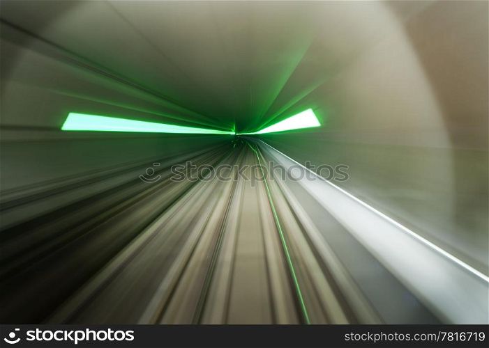 Dynamic image of a train, driving through a subway tunnel with green flares indicating emergency exits, lit by head lights.