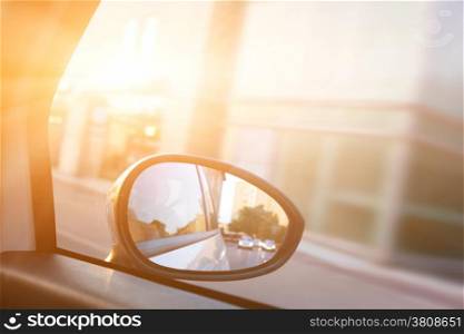 Dynamic view from car on the wing mirror during drive. Sun shining. Transportation, travel, speed.