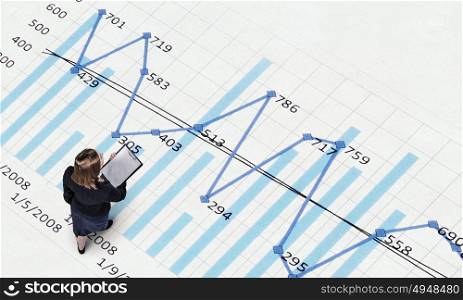 Dynamics of growth in business. Top view of businesswoman and graphs and diagrams on floor
